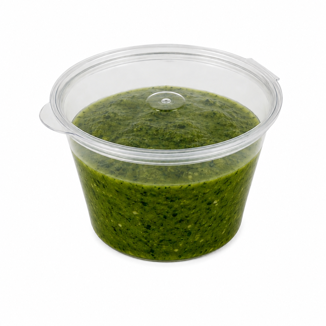 4oz clear hinged sauce pot with closed lid filled with green pesto sauce on a white background.