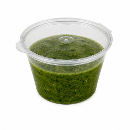 4oz clear hinged sauce pot with closed lid filled with green pesto sauce on a white background.