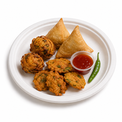 9-inch round bagasse plate served with vegetable pakoras and sweet chilli dipping sauce on a white background.